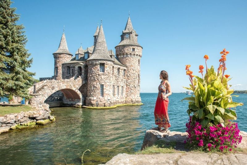 在从纽约出发的公路旅行中，一名女子在1000个岛屿的博尔特城堡前摆姿势