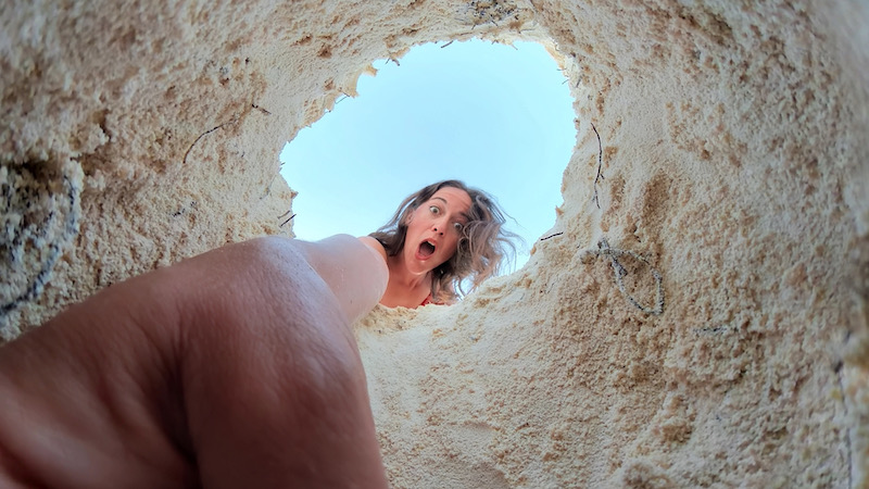 女旅游博主在沙bob游戏app手机下载bobapp网页版滩上挖沙子