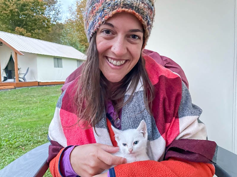 在吉尔伯特维尔农场，一位妇女抱着一只白色的小猫