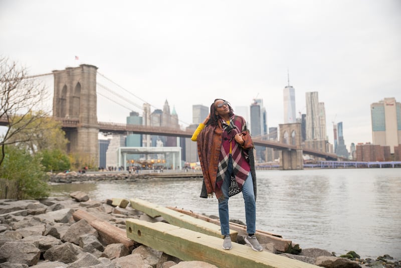 在一次纽约建筑之旅中，一名女子在DUMBO曼哈顿天际线前摆姿势