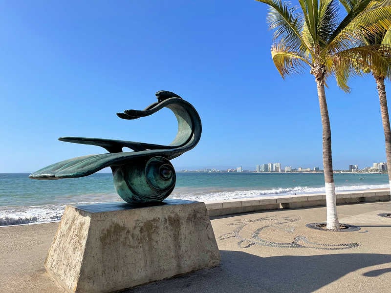 在墨西哥巴亚尔塔港独自旅行时，一名女子正在欣赏自然科摩马德雷雕塑